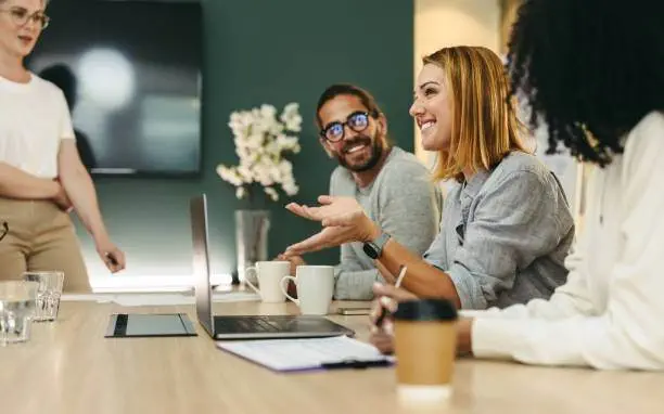 diverse people sat around a desk with a laptop on it
